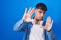 Young hispanic man standing over blue background doing frame using hands palms and fingers, camera perspective Royalty Free Stock Photo