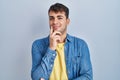 Young hispanic man standing over blue background looking confident at the camera smiling with crossed arms and hand raised on chin Royalty Free Stock Photo