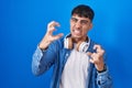 Young hispanic man standing over blue background shouting frustrated with rage, hands trying to strangle, yelling mad Royalty Free Stock Photo