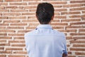 Young hispanic man standing over brick wall background standing backwards looking away with crossed arms Royalty Free Stock Photo
