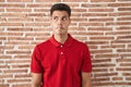 Young hispanic man standing over bricks wall making fish face with lips, crazy and comical gesture Royalty Free Stock Photo