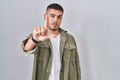 Young hispanic man standing over isolated background pointing with finger up and angry expression, showing no gesture Royalty Free Stock Photo