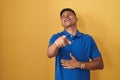 Young hispanic man standing over yellow background laughing at you, pointing finger to the camera with hand over body, shame Royalty Free Stock Photo