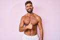 Young hispanic man standing shirtless doing happy thumbs up gesture with hand Royalty Free Stock Photo