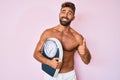 Young hispanic man standing shirtless holding weighing machine smiling happy and positive, thumb up doing excellent and approval Royalty Free Stock Photo