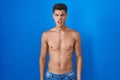 Young hispanic man standing shirtless over blue background in shock face, looking skeptical and sarcastic, surprised with open Royalty Free Stock Photo