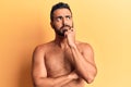 Young hispanic man standing shirtless serious face thinking about question with hand on chin, thoughtful about confusing idea Royalty Free Stock Photo