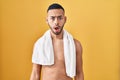 Young hispanic man standing shirtless with towel in shock face, looking skeptical and sarcastic, surprised with open mouth Royalty Free Stock Photo