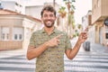 Young hispanic man standing at the street smiling and looking at the camera pointing with two hands and fingers to the side Royalty Free Stock Photo