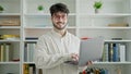 Young hispanic man student smiling confident using laptop at library university Royalty Free Stock Photo