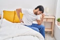 Young hispanic man suffering for back ache sitting on bed at bedroom Royalty Free Stock Photo