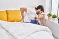 Young hispanic man suffering for back ache sitting on bed at bedroom Royalty Free Stock Photo