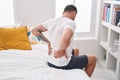 Young hispanic man suffering for back injury sitting on bed at bedroom Royalty Free Stock Photo