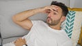 Young hispanic man suffering for headache lying on sofa at home Royalty Free Stock Photo