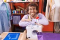 Young hispanic man tailor smiling confident leaning on sewing machine at atelier Royalty Free Stock Photo