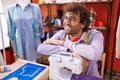 Young hispanic man tailor smiling confident leaning on sewing machine at atelier Royalty Free Stock Photo