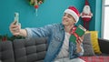 Young hispanic man taking a selfie picture holding christmas gift at home