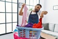 Young hispanic man talking on the smartphone while doing chores at home Royalty Free Stock Photo