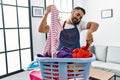 Young hispanic man talking on the smartphone while doing chores at home Royalty Free Stock Photo