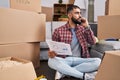 Young hispanic man talking on smartphone reading document at new home Royalty Free Stock Photo