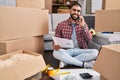 Young hispanic man talking on smartphone reading document at new home Royalty Free Stock Photo