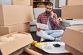 Young hispanic man talking on smartphone reading document at new home Royalty Free Stock Photo