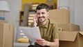 Young hispanic man talking on smartphone reading document at new home Royalty Free Stock Photo