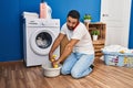 Young hispanic man talking on the smartphone wringing out rag at laundry room Royalty Free Stock Photo