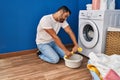 Young hispanic man talking on the smartphone wringing out rag at laundry room Royalty Free Stock Photo