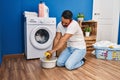 Young hispanic man talking on the smartphone wringing out rag at laundry room Royalty Free Stock Photo