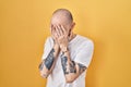 Young hispanic man with tattoos standing over yellow background with sad expression covering face with hands while crying Royalty Free Stock Photo