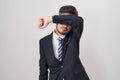 Young hispanic man with tattoos wearing business suit and tie covering eyes with arm, looking serious and sad Royalty Free Stock Photo