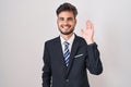 Young hispanic man with tattoos wearing business suit and tie waiving saying hello happy and smiling, friendly welcome gesture Royalty Free Stock Photo
