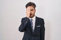 Young hispanic man with tattoos wearing business suit and tie yawning tired covering half face, eye and mouth with hand Royalty Free Stock Photo