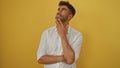 Young, hispanic, man, with, thoughtful, expression, over, isolated, yellow, background Royalty Free Stock Photo