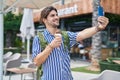 Young hispanic man tourist making selfie by smartphone eating ice cream at street Royalty Free Stock Photo