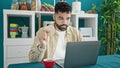 Young hispanic man using laptop having breakfast at dinning room Royalty Free Stock Photo