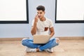 Young hispanic man using laptop at home pointing to the eye watching you gesture, suspicious expression Royalty Free Stock Photo