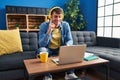 Young hispanic man using laptop at home smiling with an idea or question pointing finger with happy face, number one Royalty Free Stock Photo