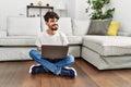 Young hispanic man using laptop sitting on the floor at home Royalty Free Stock Photo
