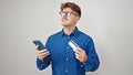 Young hispanic man using smartphone and credit card thinking over isolated white background Royalty Free Stock Photo