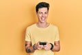 Young hispanic man using smartphone typing message winking looking at the camera with sexy expression, cheerful and happy face Royalty Free Stock Photo