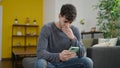 Young hispanic man using smartphone worried sitting on the sofa at home Royalty Free Stock Photo