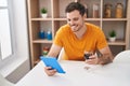 Young hispanic man using touchpad drinkng wine at home