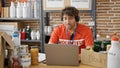 Young hispanic man volunteer writing on clipboard having video call at charity center