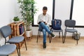 Young hispanic man waiting filling documents on clipboard at waiting room Royalty Free Stock Photo
