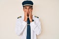 Young hispanic man wearing airplane pilot uniform tired hands covering face, depression and sadness, upset and irritated for Royalty Free Stock Photo