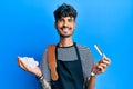 Young hispanic man wearing barber apron holding razor and foam smiling with a happy and cool smile on face