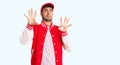 Young hispanic man wearing baseball uniform afraid and terrified with fear expression stop gesture with hands, shouting in shock Royalty Free Stock Photo