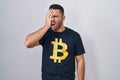 Young hispanic man wearing bitcoin t shirt yawning tired covering half face, eye and mouth with hand Royalty Free Stock Photo